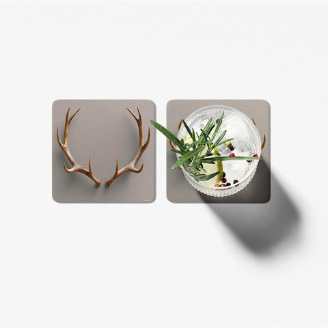 Two coasters with deer antlers and a cocktail on a light gray background