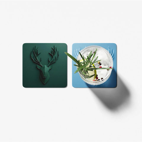 Two coasters, one with a deer head design and the other with a cocktail, on a white background.