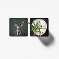 Two coasters with a deer in a suit and a cocktail with herbs on a white background