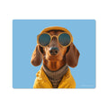A vinyl mouse pad with a whimsical image of a dog wearing sunglasses and a yellow jacket against a blue background.