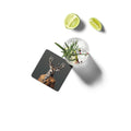 Coaster with deer design next to a cocktail with lime wedges on a white background